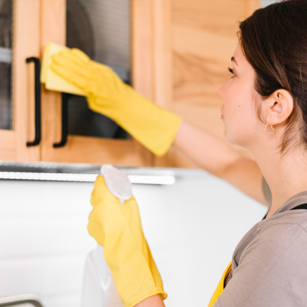 woman sanitising kitchen door handles